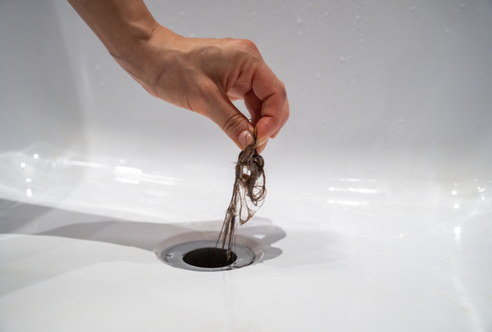 Home Hand pulling hair from a clogged bathtub drain, showing a common plumbing issue caused by hair buildup. Flow Pro Plumbing provides professional bathtub drain cleaning, hair clog removal, and clogged drain services for homeowners searching how to unclog bathtub full of hair. Contact us today for help with how to unclog bathtub full of hair, bathtub drain clogged with hair, best way to remove hair from bathtub drain, unclog bathtub drain hair removal, clogged tub drain fix, hair clog in bathtub drain, drain cleaning near me, bathtub plumbing repair, professional drain unclogging service, Flow Pro Plumbing hair clog removal, slow bathtub drain fix, emergency plumber for clogged tub, drain cleaning services near me, plumber to unclog bathtub, hydro jetting services near me, drain snaking service near me, tub drain backed up with hair, affordable bathtub drain repair, shower drain hair removal, local plumbing services for clogged drains.